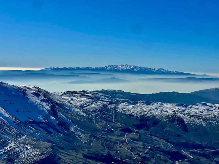 Picture of the mountains from Faraya in Lebanon. It shows a green valley and mountains covered by snow.